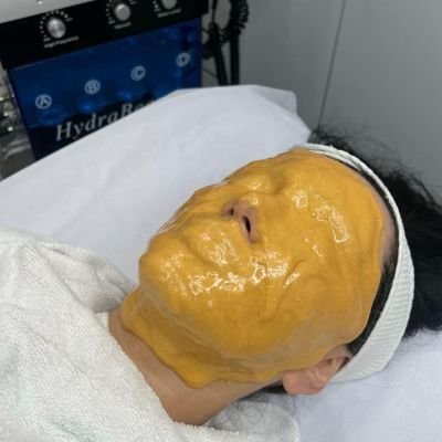 Woman with an orange facial mask during a skincare treatment.